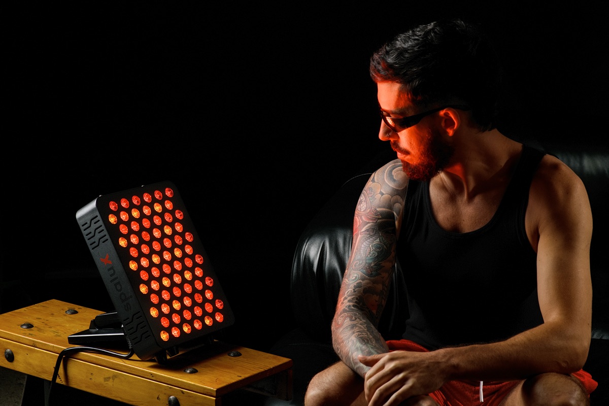A man seated beside the lit Spalux Glow panel on a wooden bench