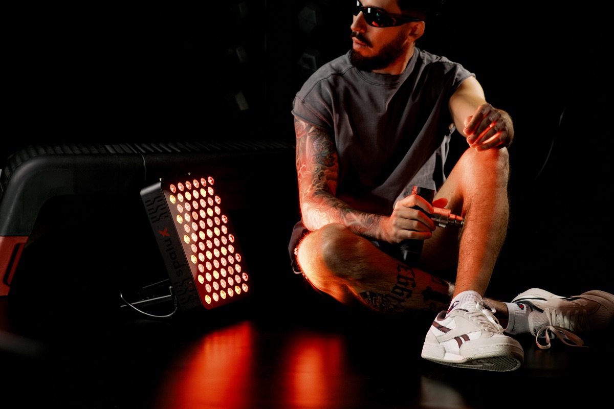 A man sitting on the floor in front of the lit Spalux Glow panel