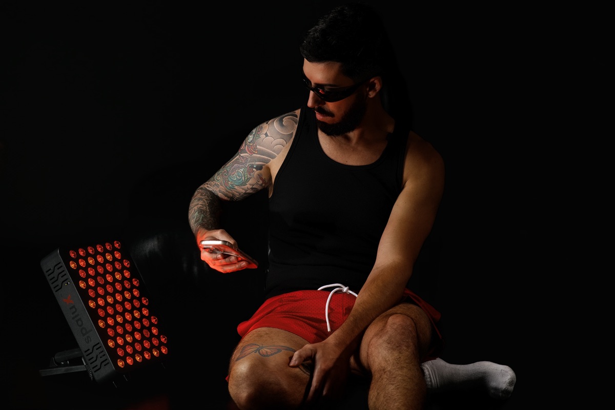A man checking his phone beside the lit Spalux Glow panel