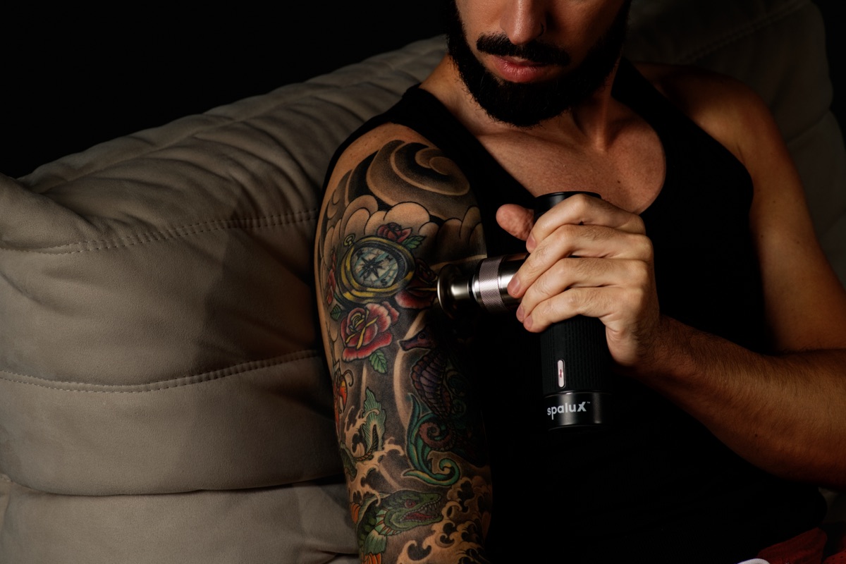 A man working the Spalux Pulse massage gun into the front of his shoulder
