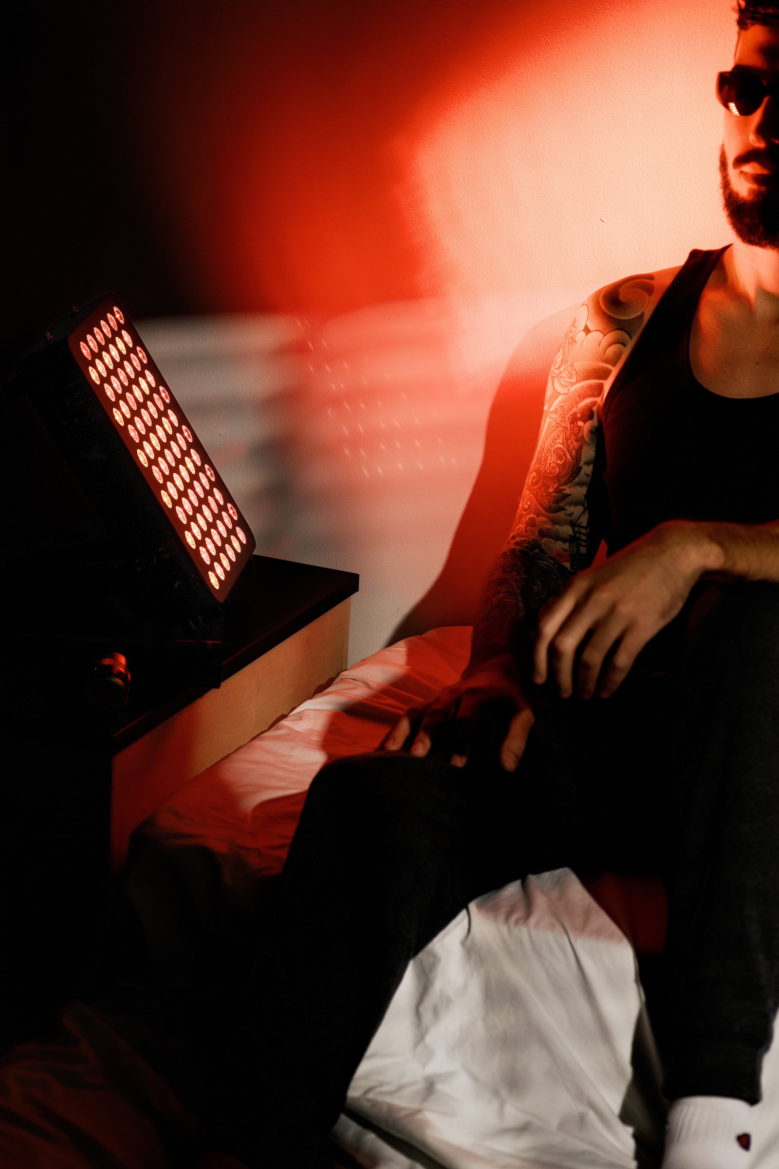 The Spalux Glow red light therapy panel in use, lighting the user in red
